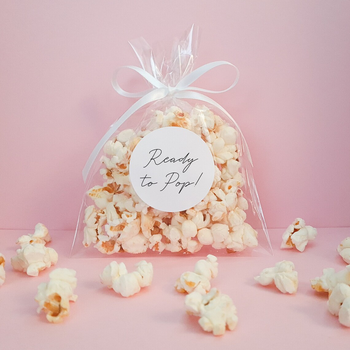 A Flat Cello Bag filled with Popcorn and tied with a white ribbon. Round label with Ready to Pop