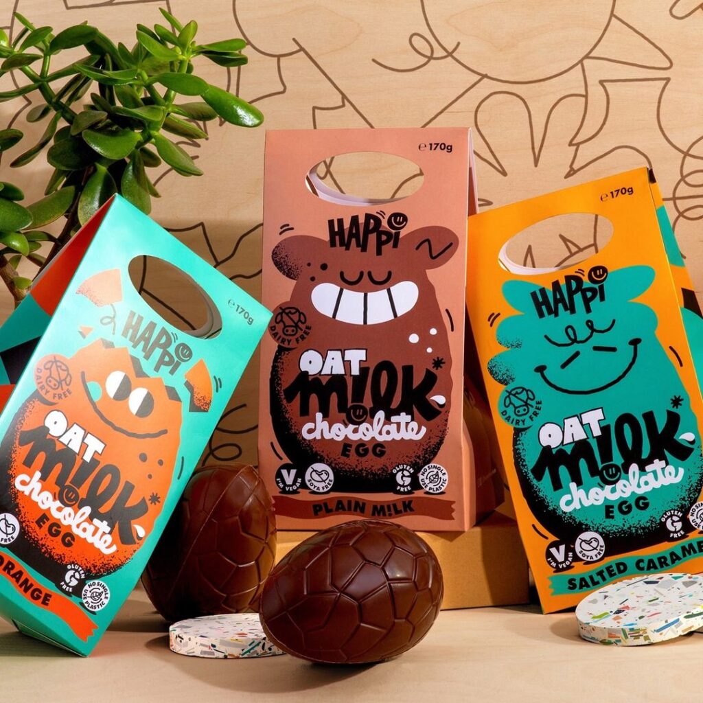 Happi Free From Large Oat Milk Chocolate Egg Cartons with handle. Blue, brown and orange cartons with cartoon graphic. 