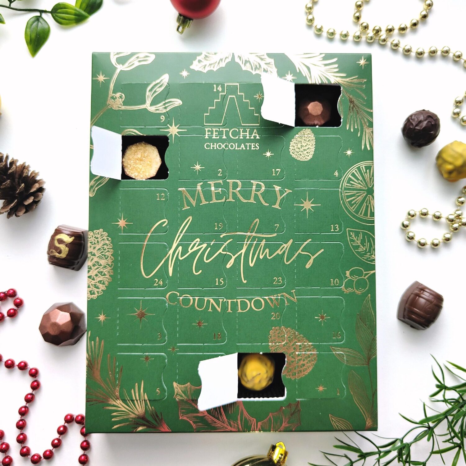 Fetcha Chocolates customised stock 24 Day Portrait Standard Advent Calendar. Green print with metallic gold foil detailing. Snowflakes, holly, berries and greenery illustrations. Filled with Alcoholic chocolate truffles