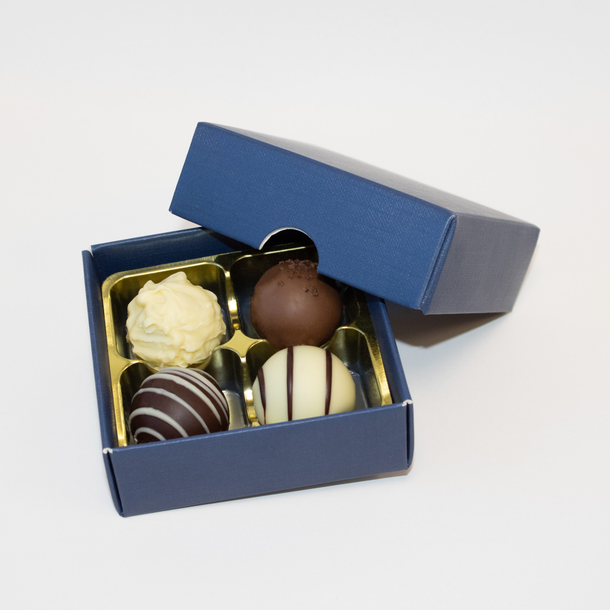 A 4 cavity Regal Blue Elegance fold-up base & lid with a bright gold vac-forme tray filled with chocolate truffles