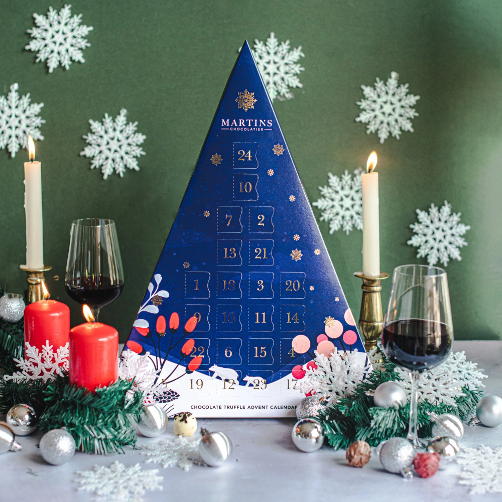 Martins Chocolatier's Blue Triangle 24 Day Advent Calendar with Bright Gold foil detailed snowflakes & numbers. In a festive winter scene